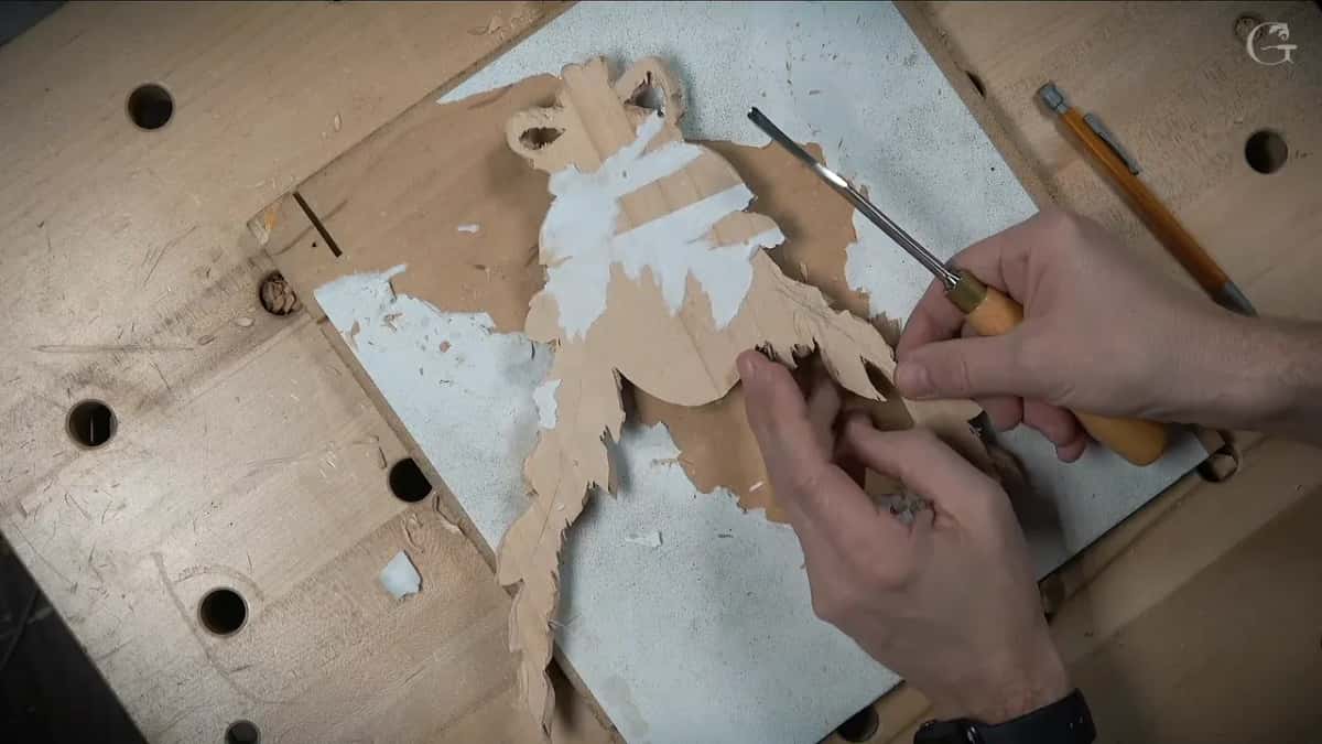 A narrow tool works the rim of a thin leaf while fingers of the other hand rest beneath it