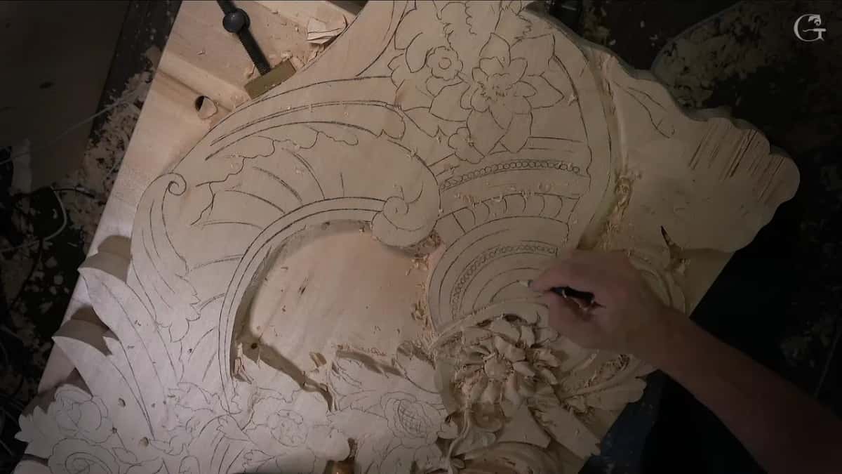 One hand draws shell lines in pencil above a flower that is already roughed out