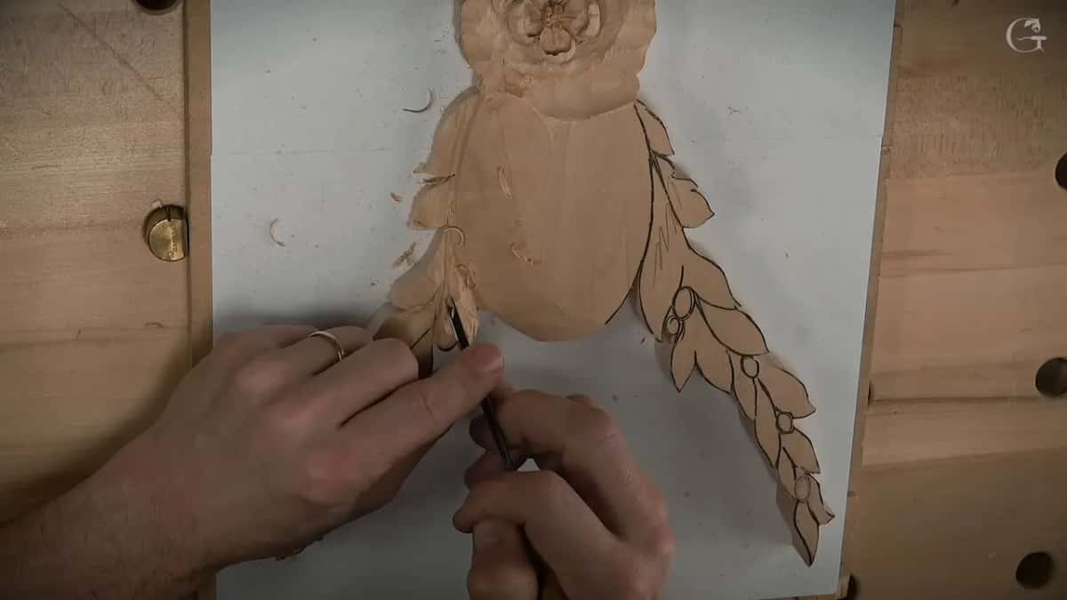 Both hands guide a small tool along the left spray, the oval still plain