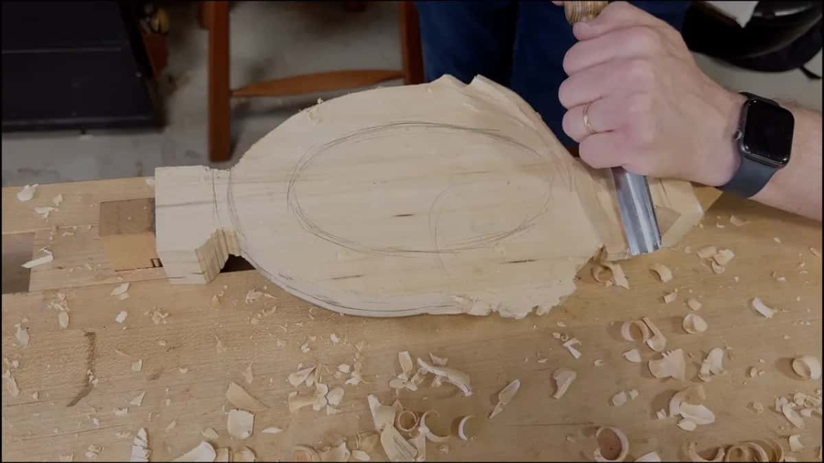 Gouge working the rim of a tray blank with an oval drawn on it, shavings all around