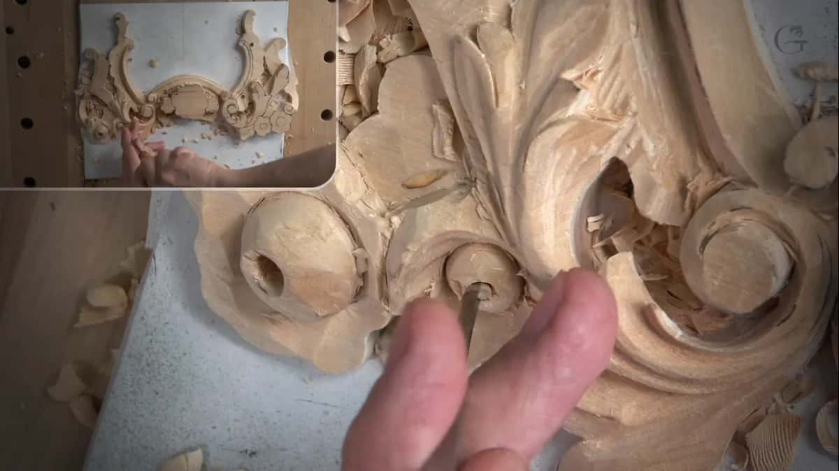 Fingers hold a narrow tool down in the small hole of the flower on the right, with the whole panel in an inset