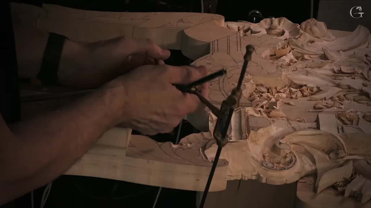 Both hands set a pointing machine on the carved panel