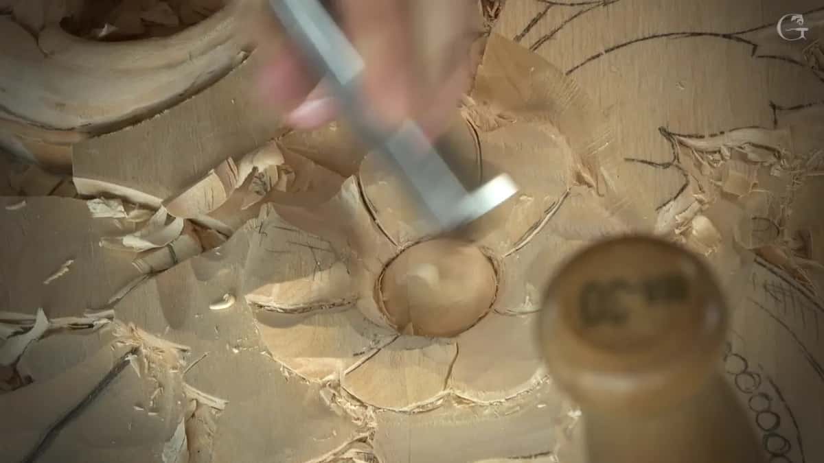 Blurred wide gouge entering a petal, a handle end close to the lens
