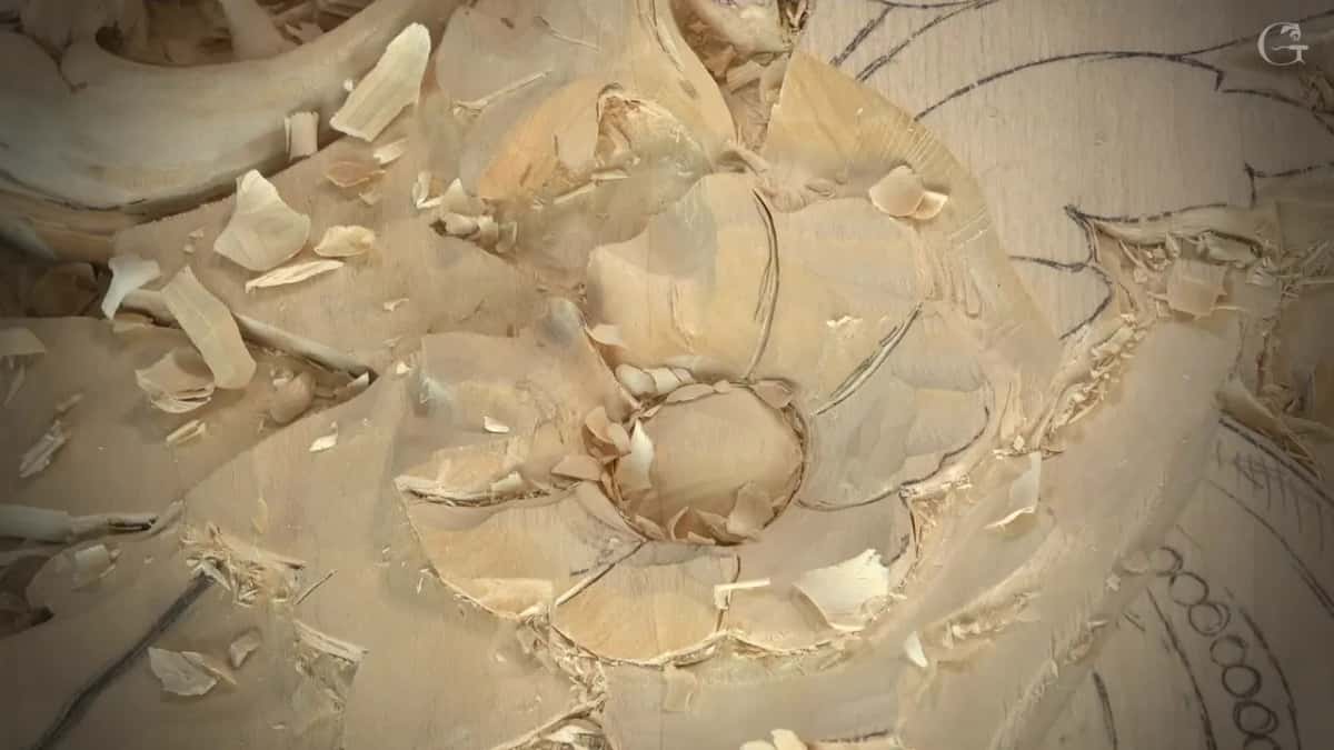 Petals with hollows and rounded ridges around a smooth round middle, shavings scattered over the panel