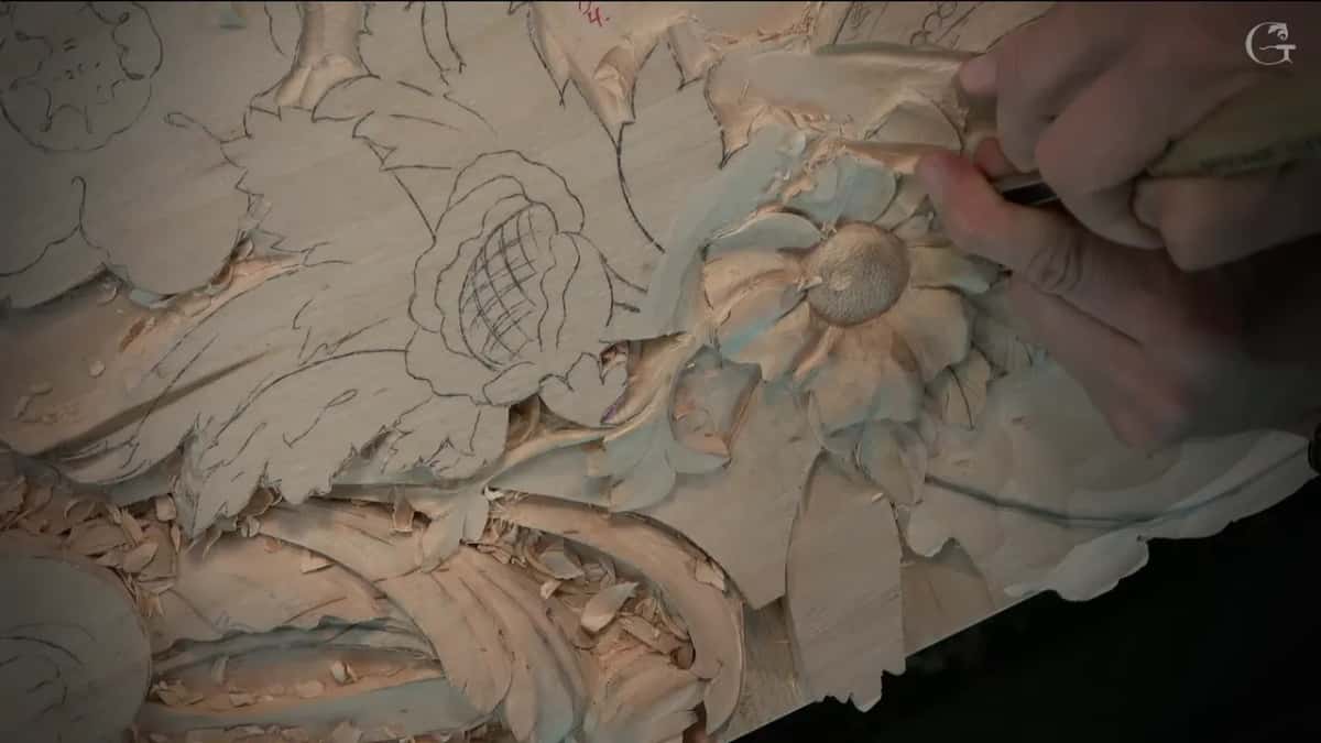 Seen low from the side, the carved petals curve up while a hand works at the right