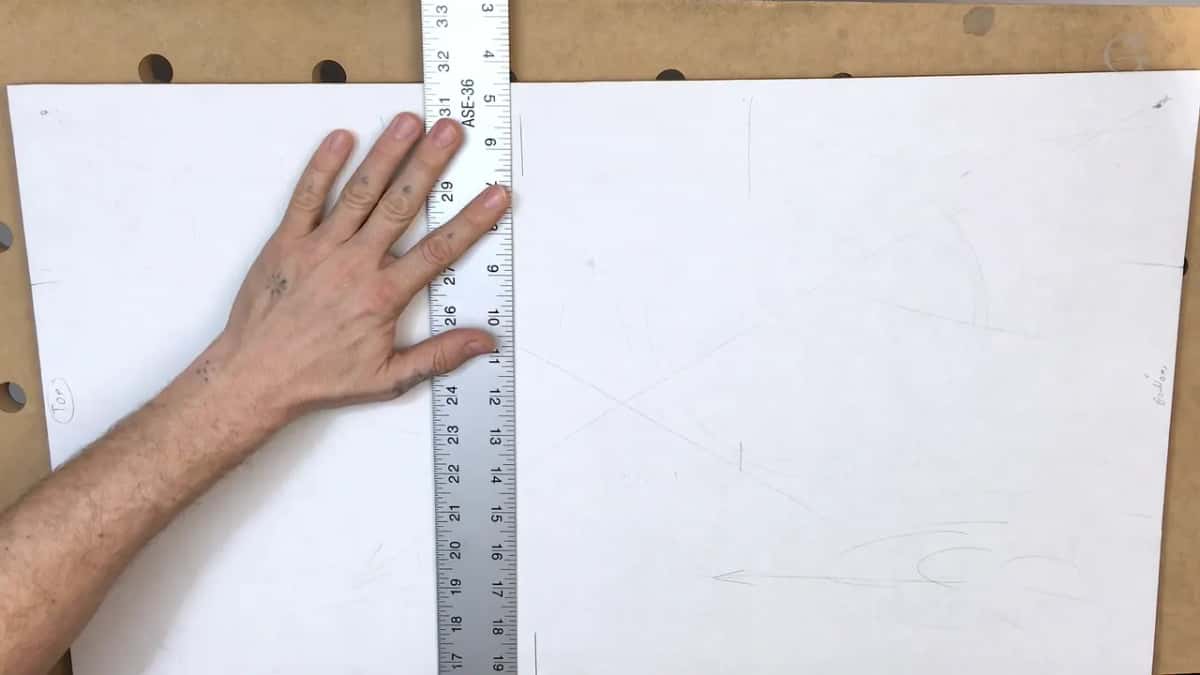 Steel ruler held flat across white paper glued over the board, ready for a measured line