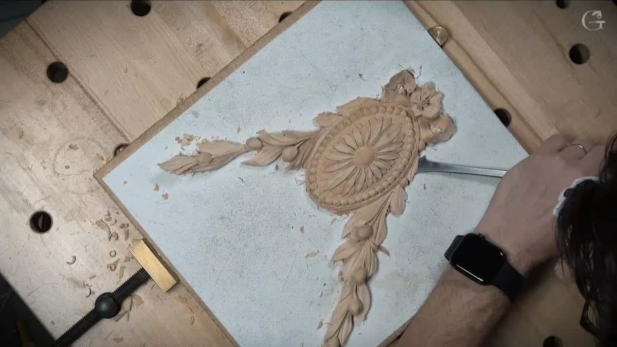 Long thin blade slid under one side of the rosette, a hand at its far end